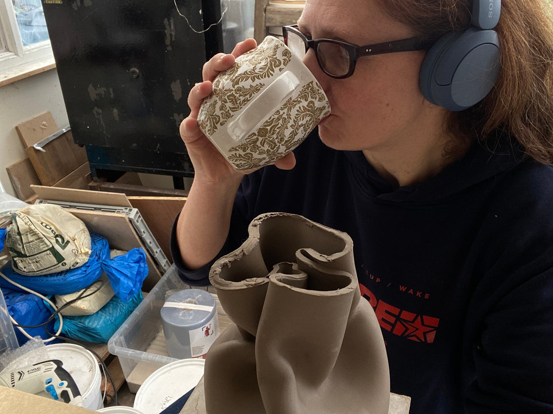 Nina in her studio drinking out of a large white patterned mug