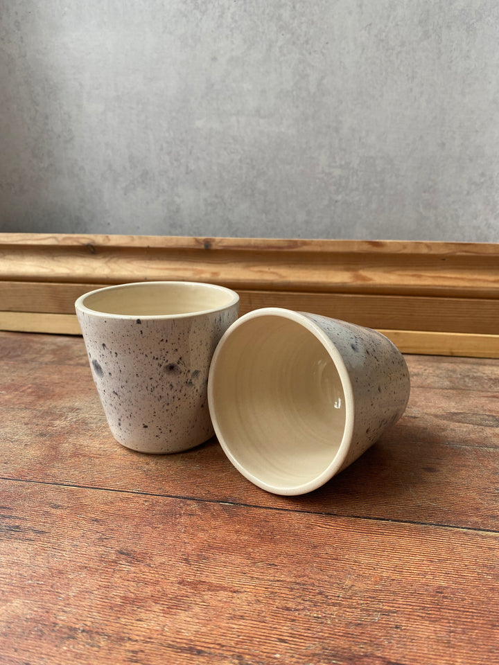 Artisan ink spot white and grey speckled ceramic coffee cup with a flared rim