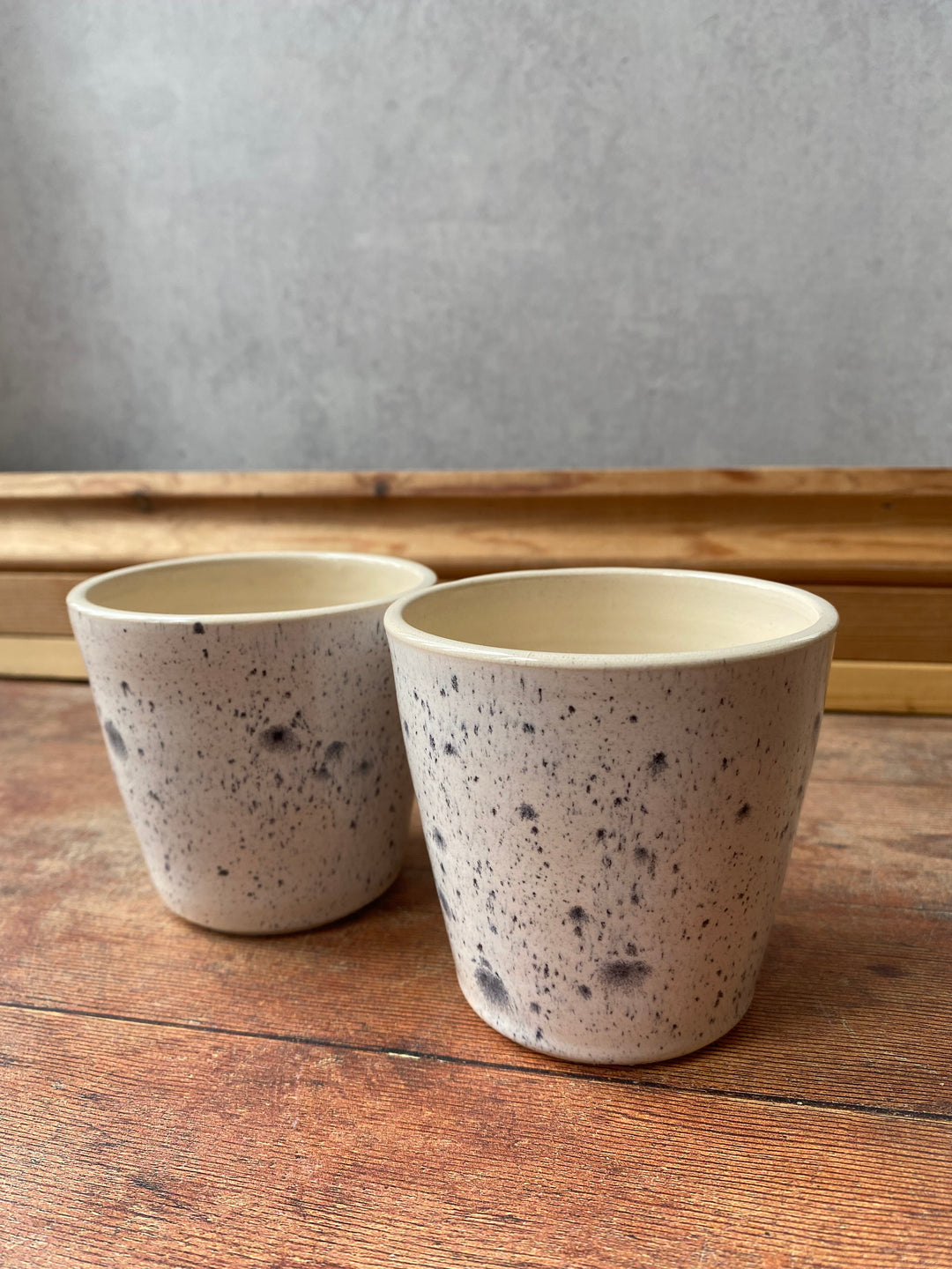 Artisan ink spot white and grey speckled ceramic coffee cup with a flared rim