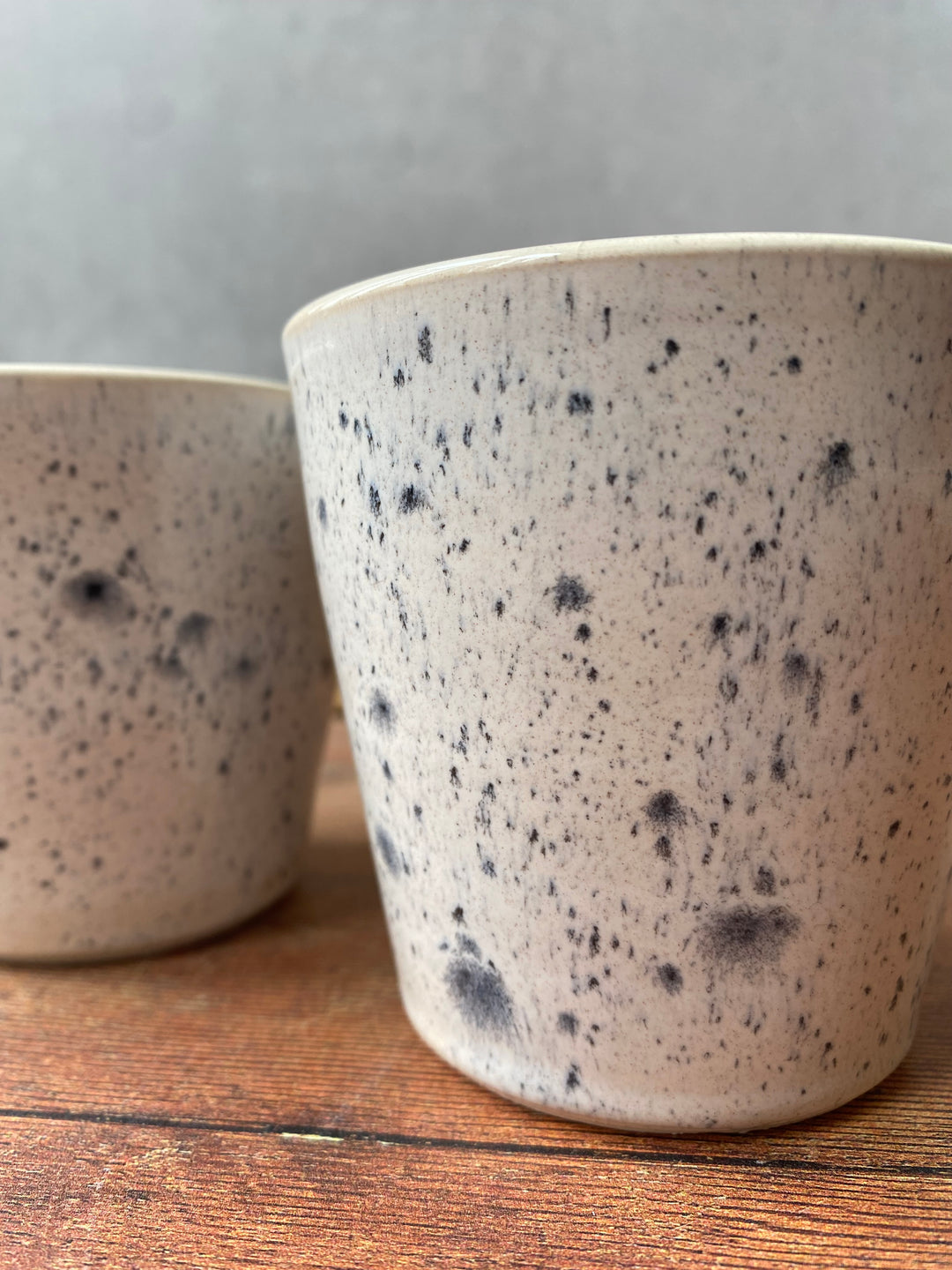Artisan ink spot white and grey speckled ceramic coffee cup with a flared rim