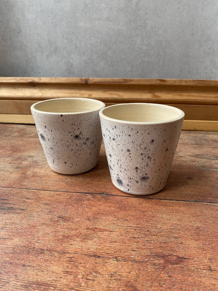 Artisan ink spot white and grey speckled ceramic coffee cup with a flared rim