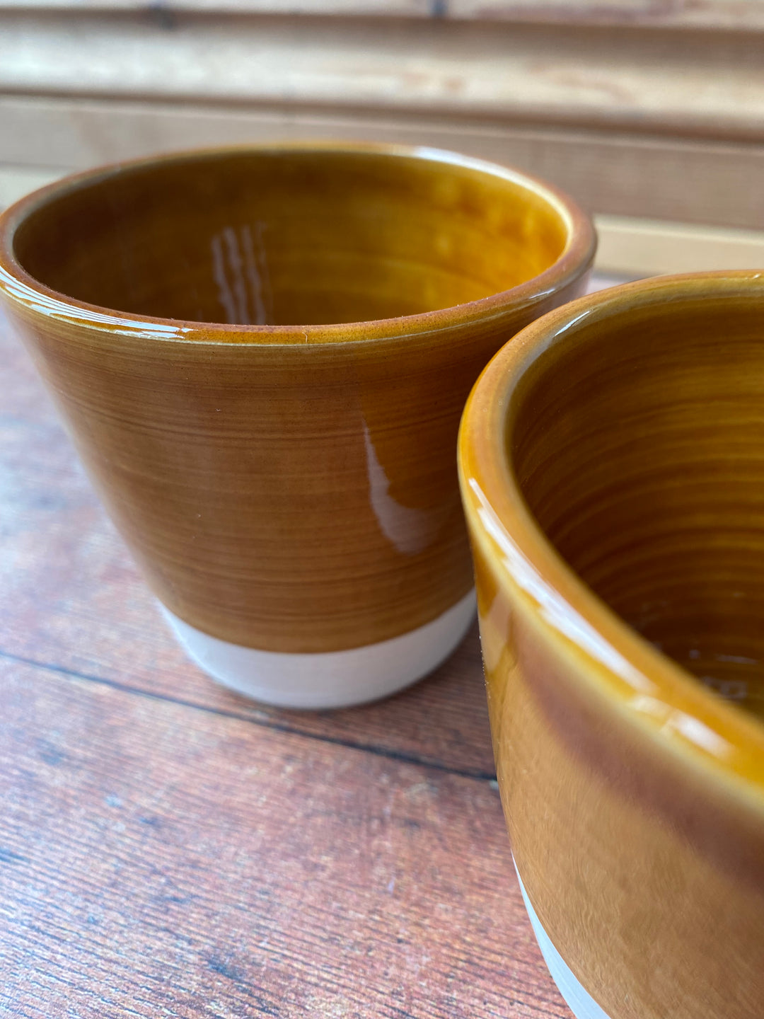 Handcrafted warm caramel V shaped latte cup held in two hands UK