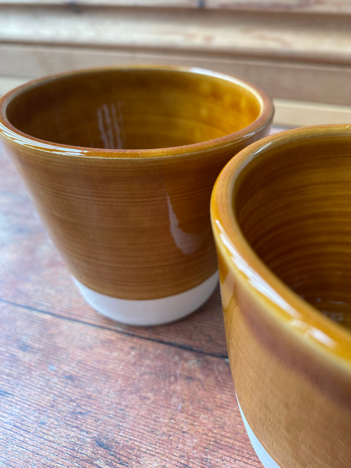 Handcrafted warm caramel V shaped latte cup held in two hands UK