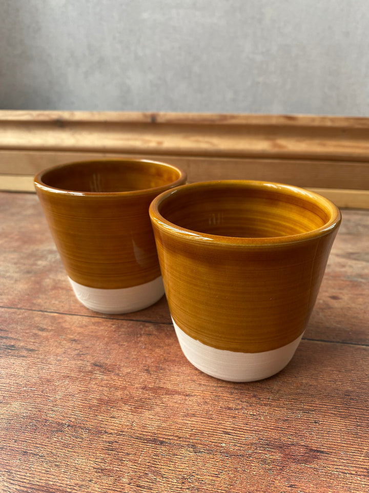 Handcrafted warm caramel stoneware V shaped latte cup held in two hands UK A