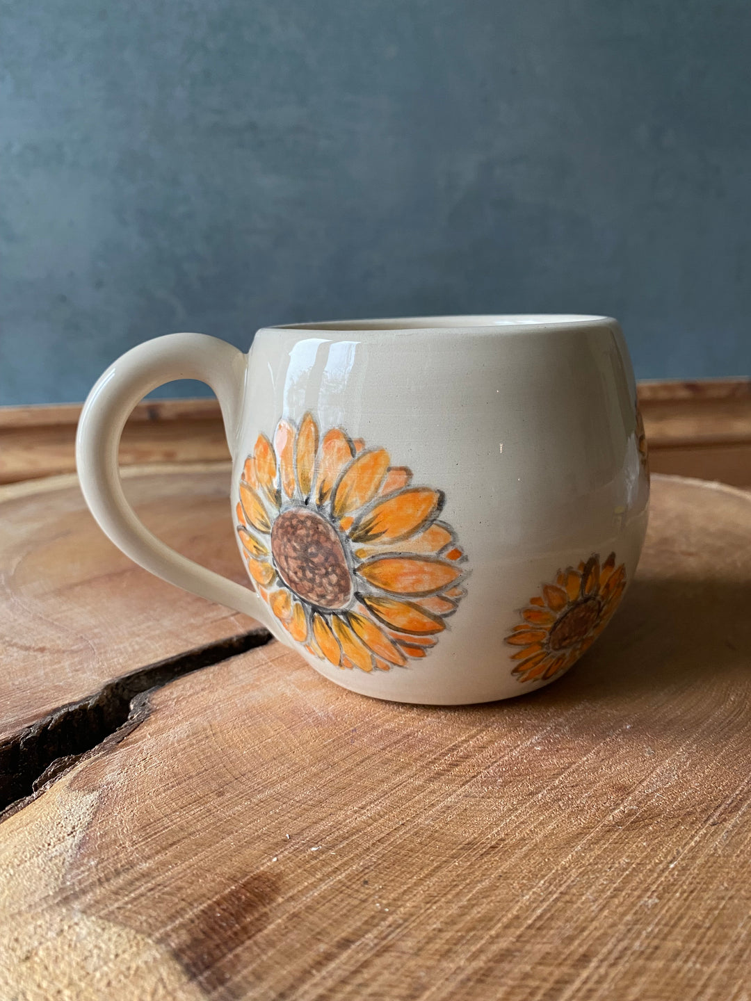 White mug with sunflower design on a wooden surface