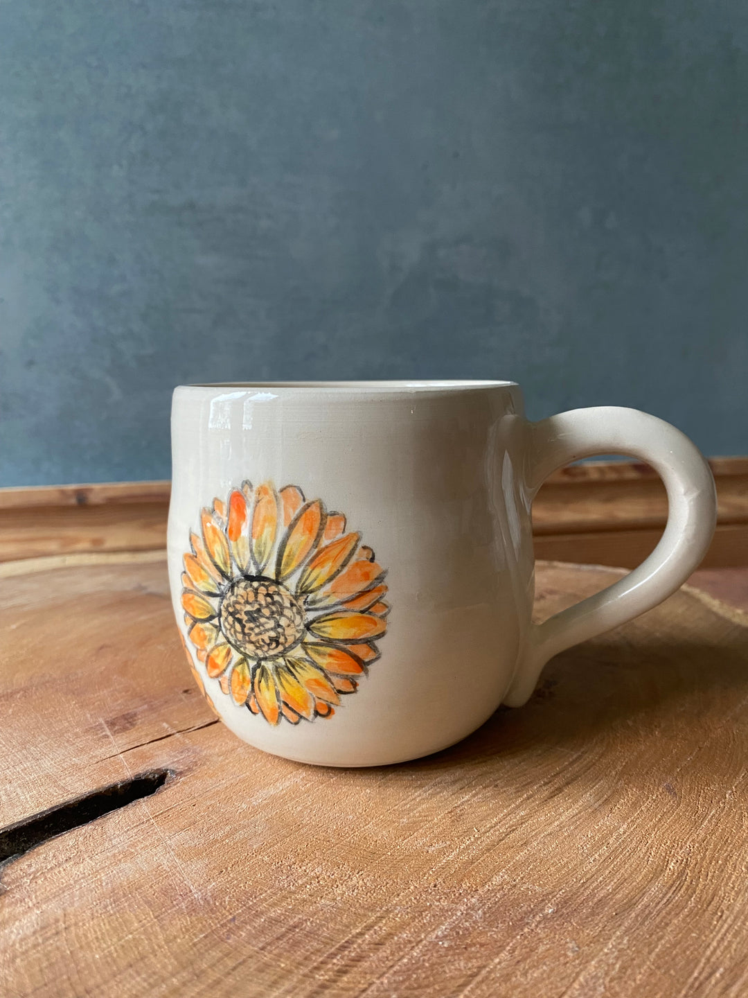 White mug with a sunflower design on a wooden surface