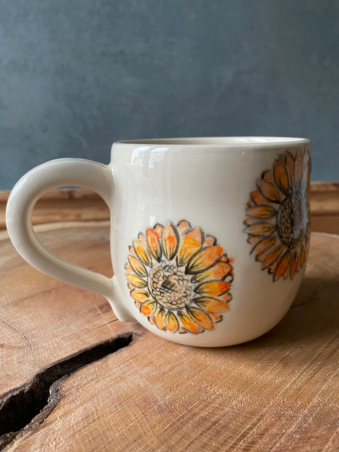 White mug with sunflower designs on a wooden surface