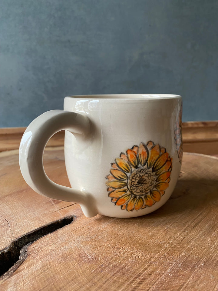 White mug with a sunflower design on a wooden surface