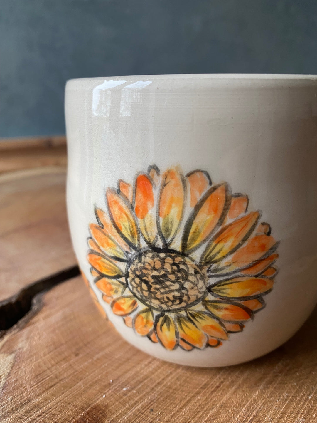 Ceramic mug with a sunflower design on a wooden surface