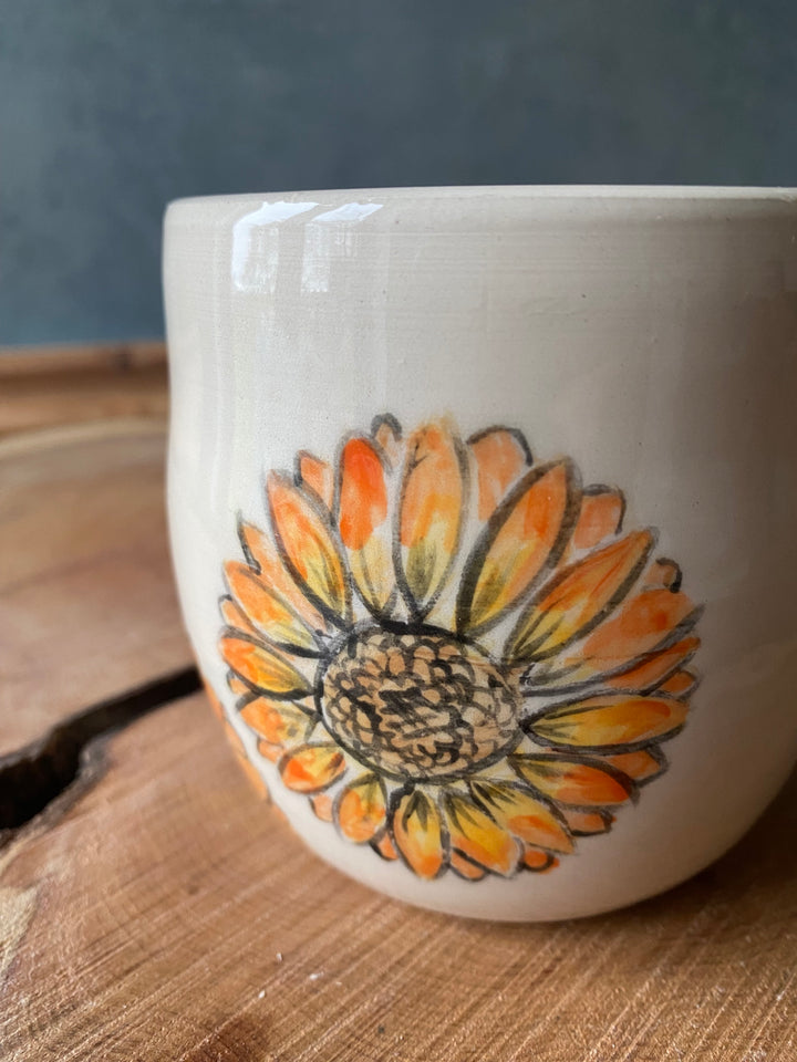 Ceramic mug with a sunflower design on a wooden surface