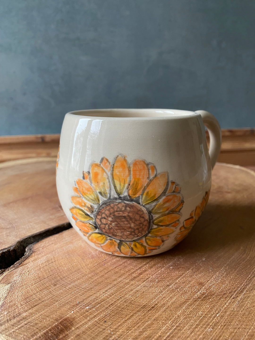 Ceramic mug with sunflower design on a wooden surface