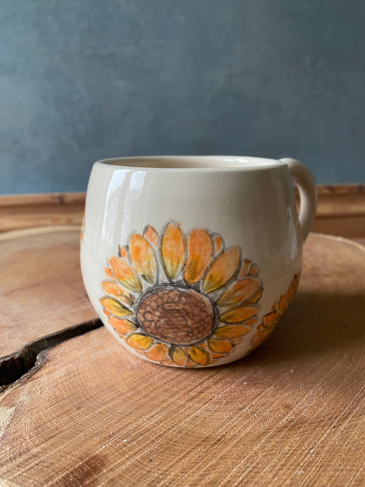 Ceramic mug with sunflower design on a wooden surface