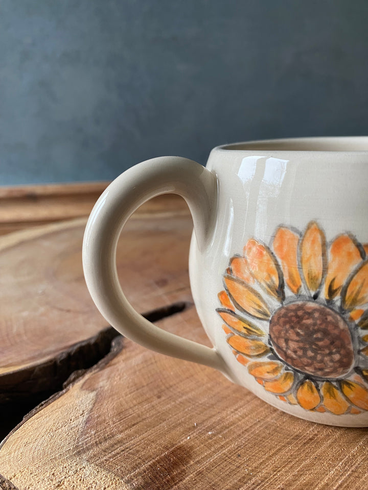 Mug with sunflower design on a wooden surface