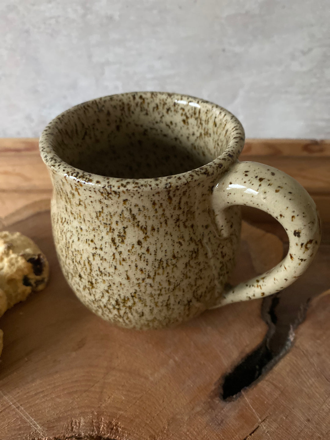 Speckled ceramic mug on a wooden surface with a neutral background