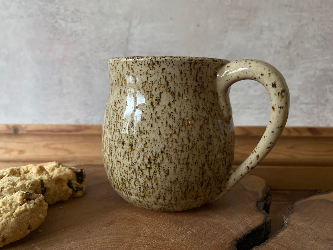 Speckled ceramic mug on a wooden surface with a light background