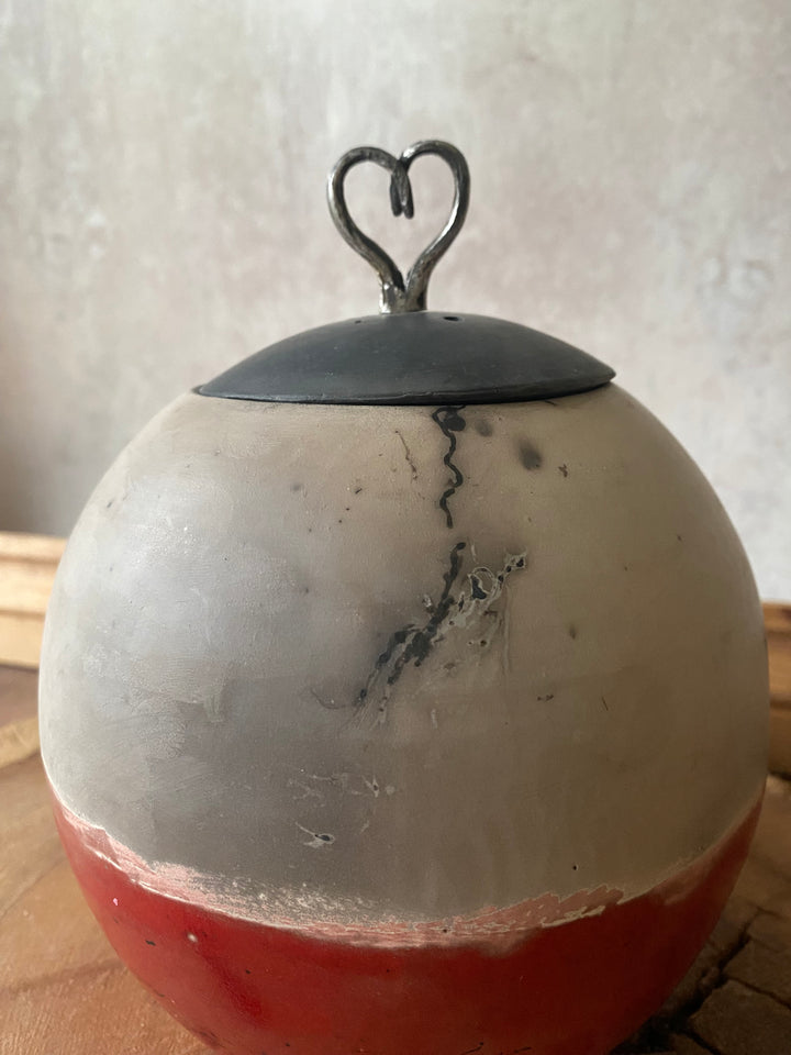 Close-up of a decorative item with a black heart-shaped ornament on a light background