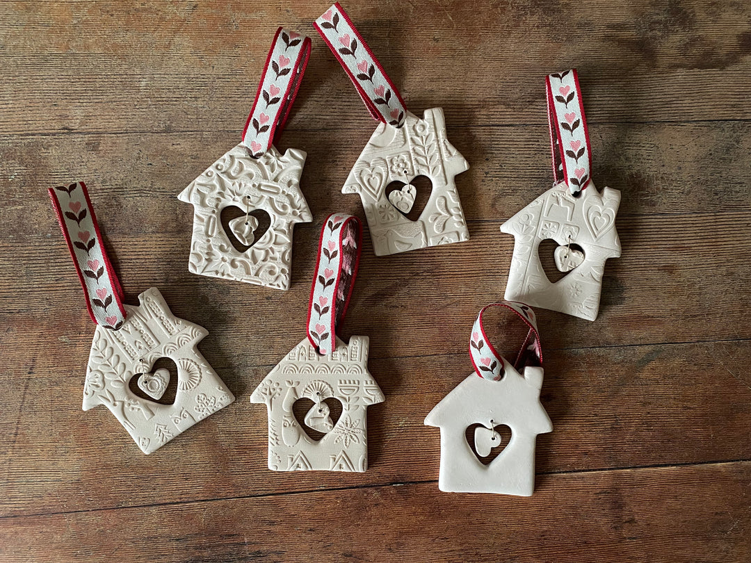 Set of ceramic house-shaped ornaments with heart cutouts on a wooden surface