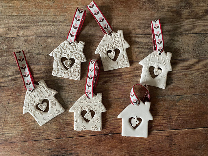 Set of ceramic house-shaped ornaments with heart cutouts on a wooden surface