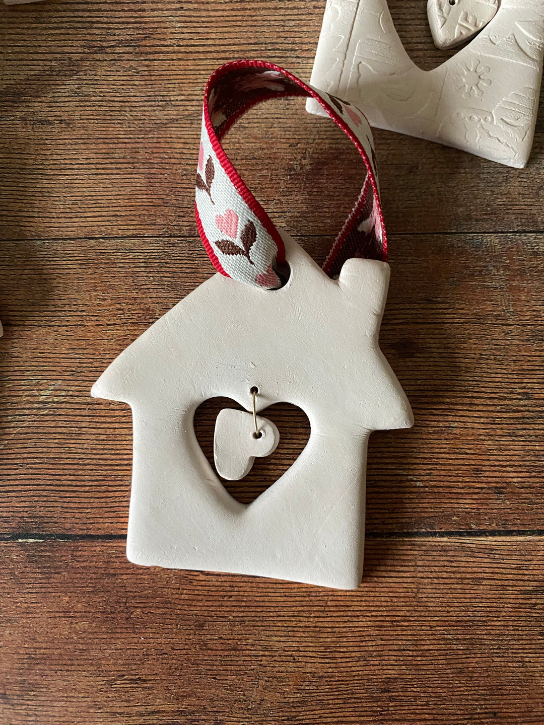 Decorative ceramic house-shaped ornament with a heart cutout on a wooden surface