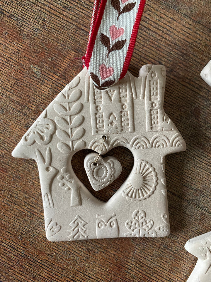 Decorative white ornament with embossed designs and a red ribbon on a wooden surface