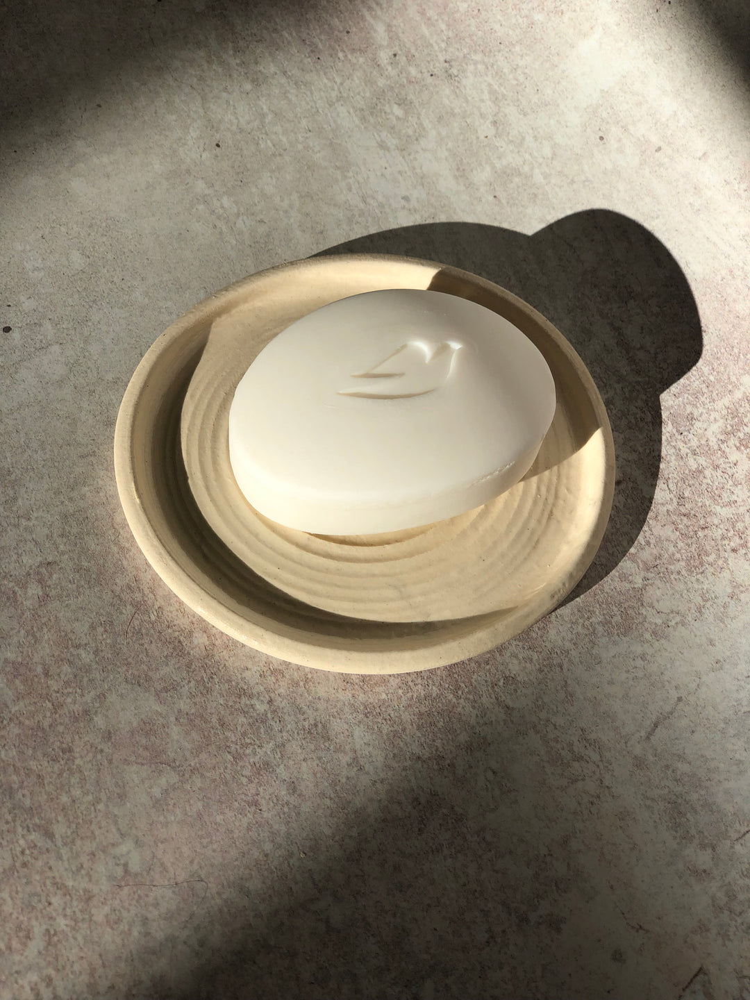 White ceramic bowl with soap on a grey surface