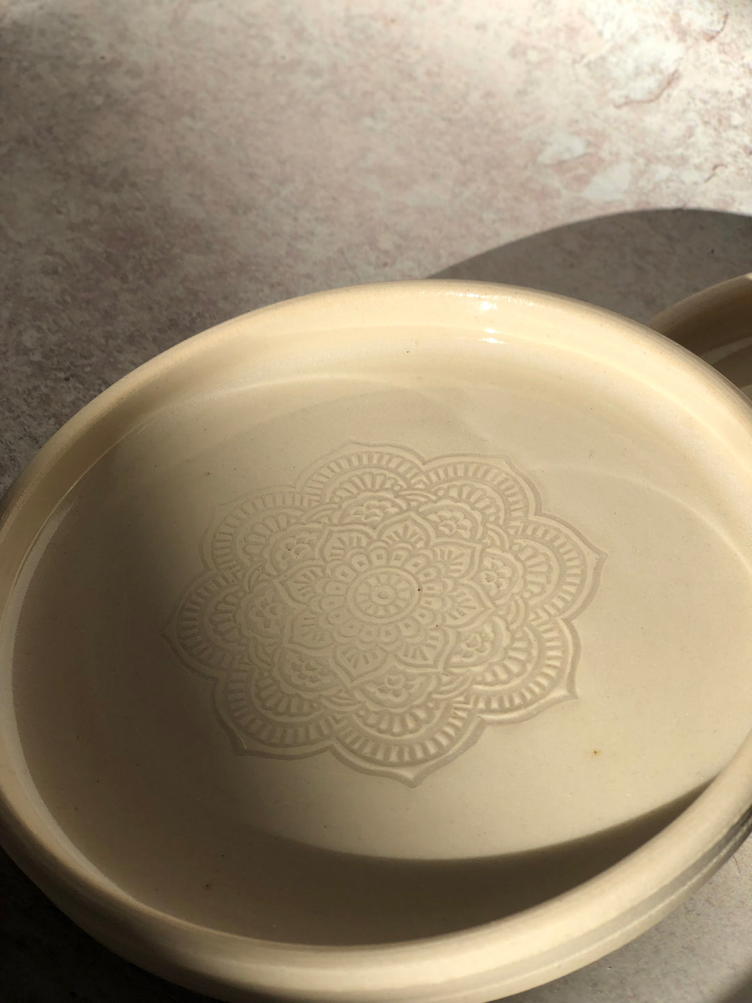 White ceramic dish with decorative pattern on a textured surface