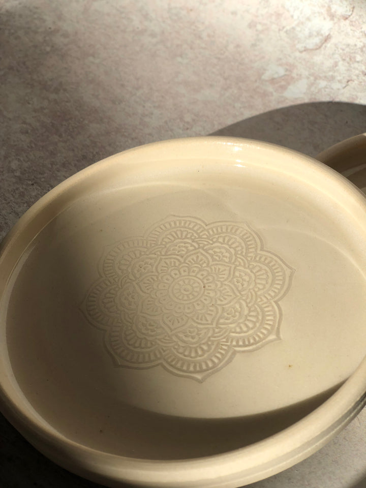 White ceramic dish with decorative pattern on a textured surface