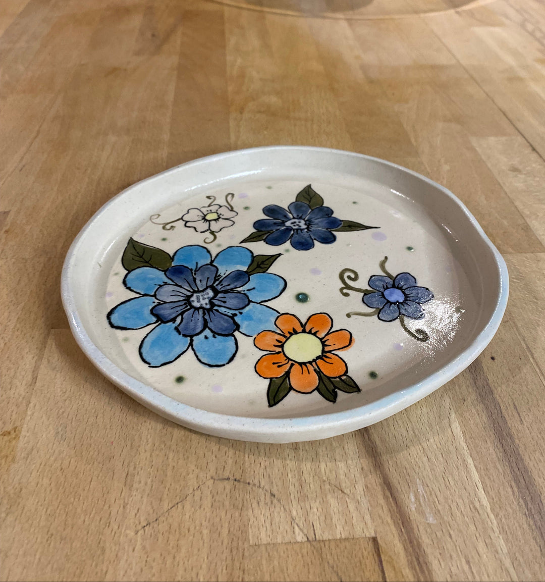 Small ceramic dish with floral designs on a wooden surface