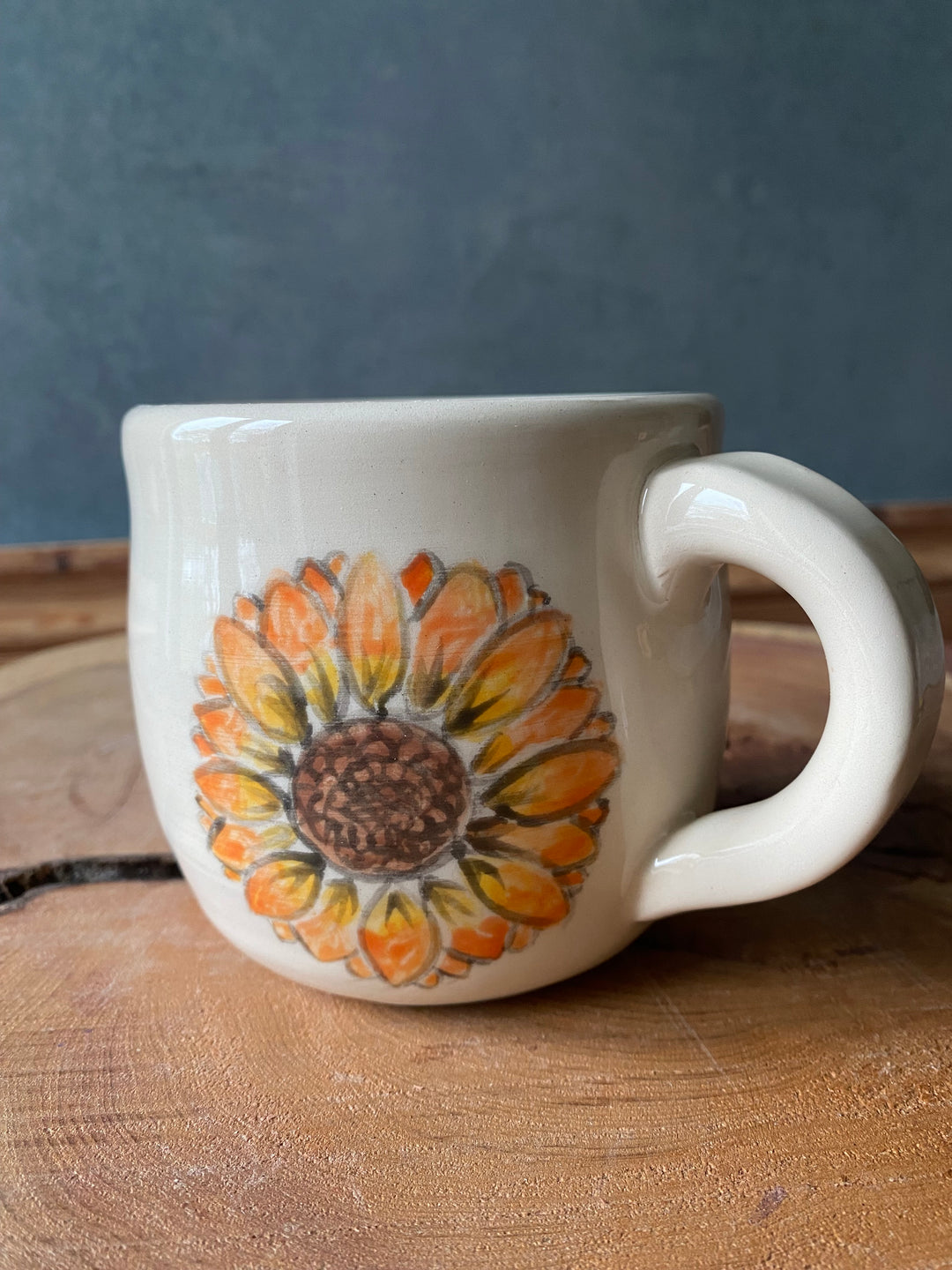 White mug with a sunflower design on a wooden surface