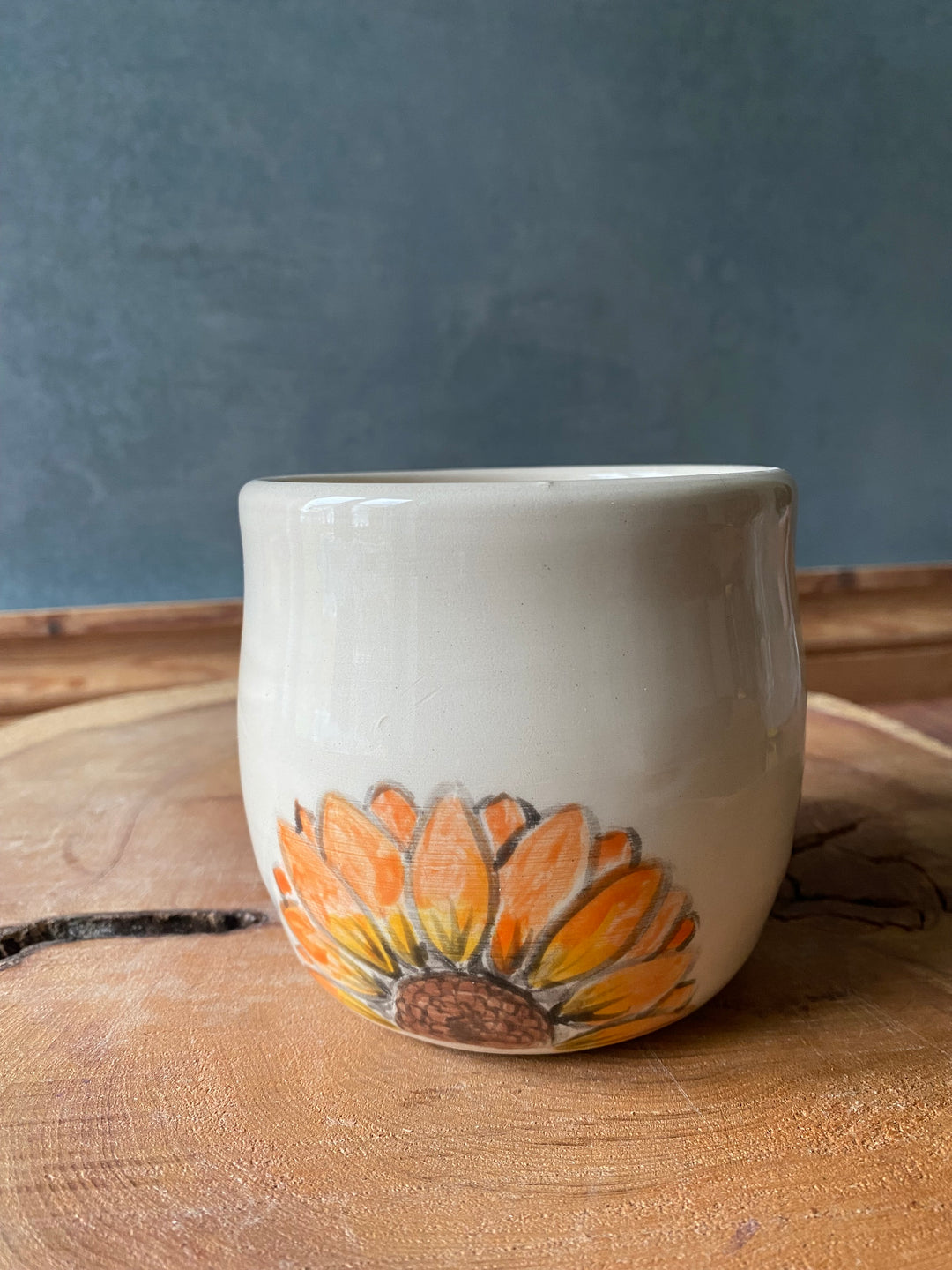Ceramic cup with sunflower design on a wooden surface