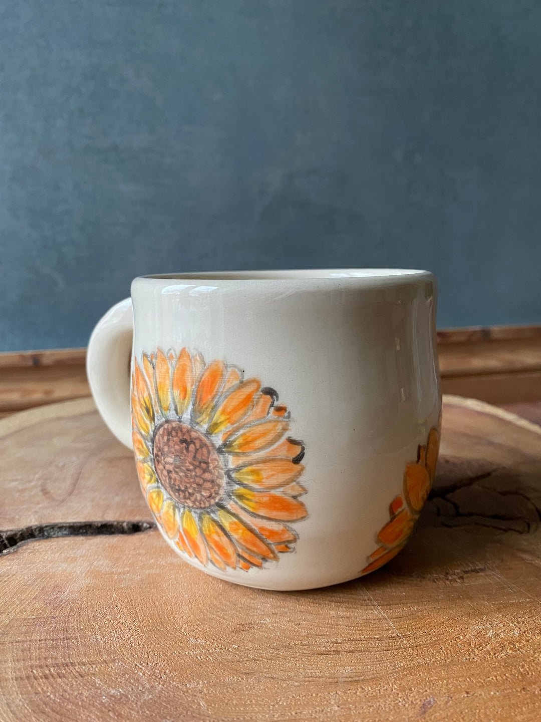 Ceramic mug with sunflower design on a wooden surface
