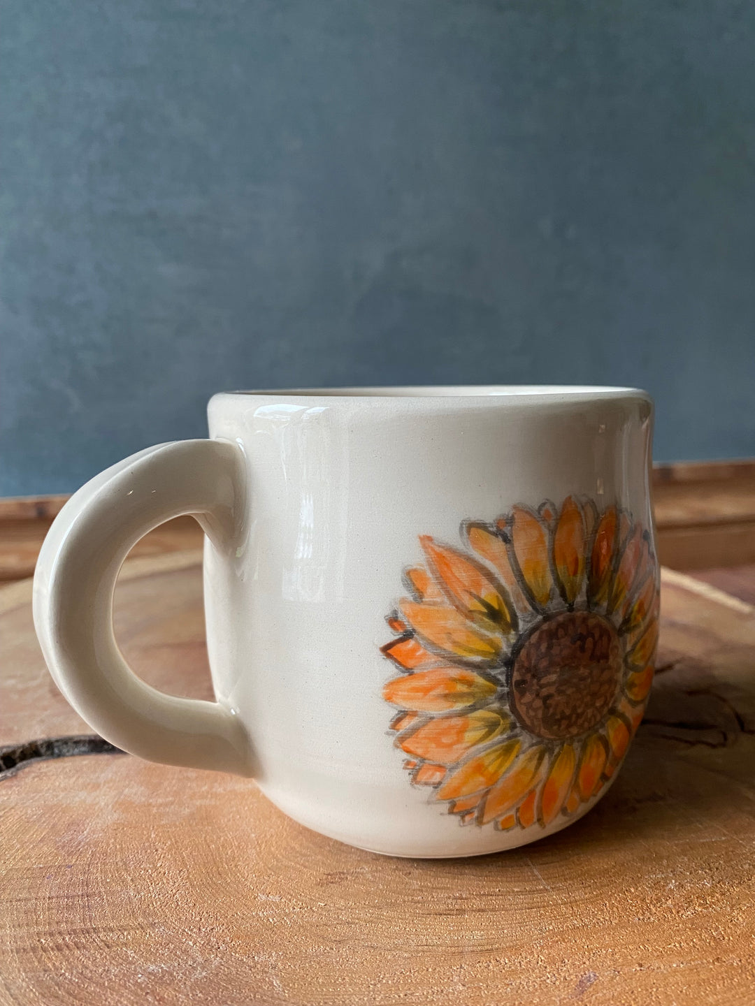 White mug with sunflower design on a wooden surface