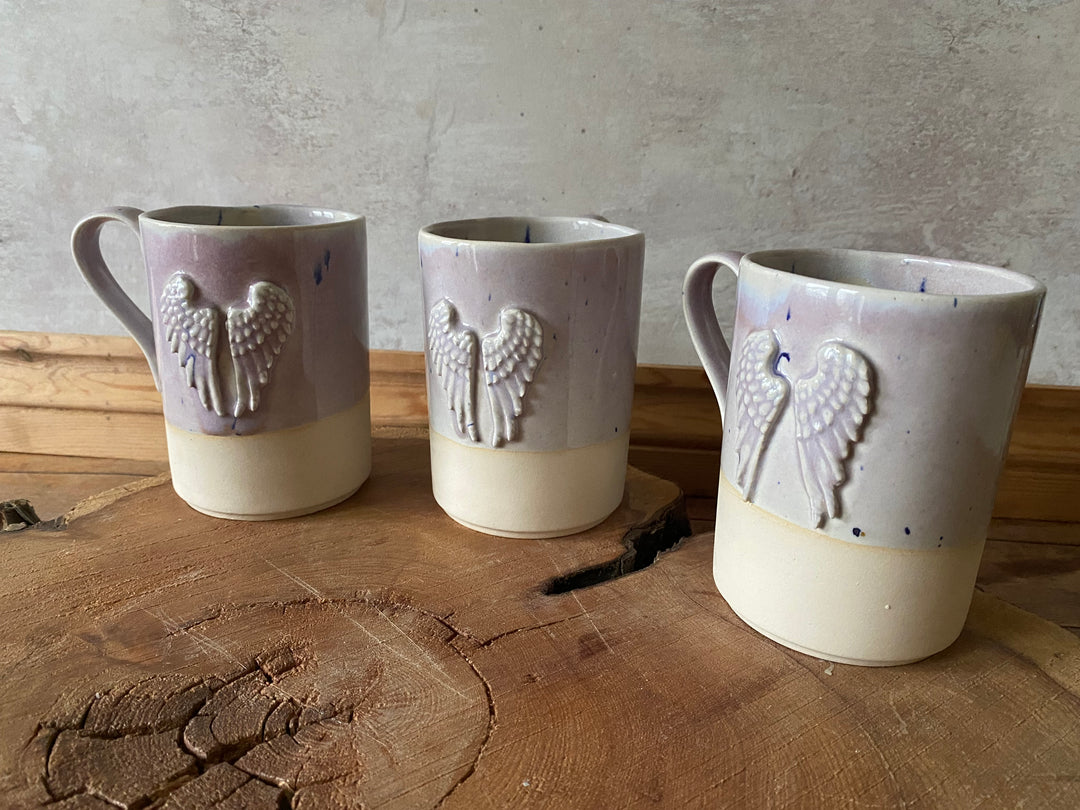 Three ceramic cups with embossed designs on a wooden surface