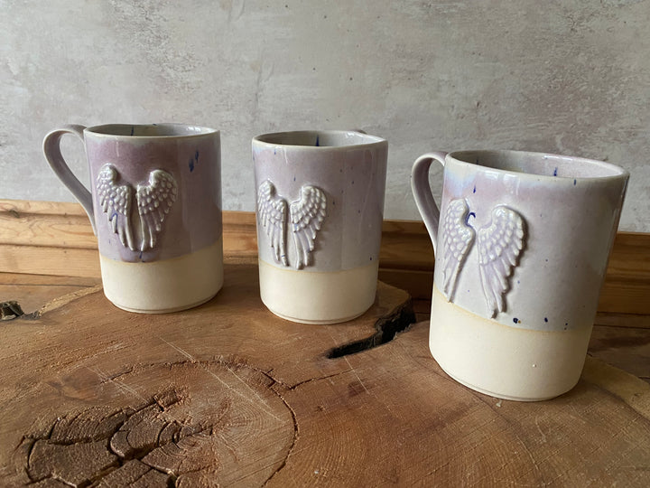 Three ceramic cups with embossed designs on a wooden surface