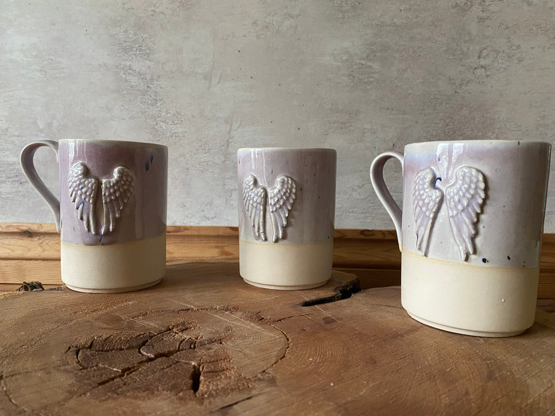 Three ceramic mugs with a Angel Wing design on a wooden surface.