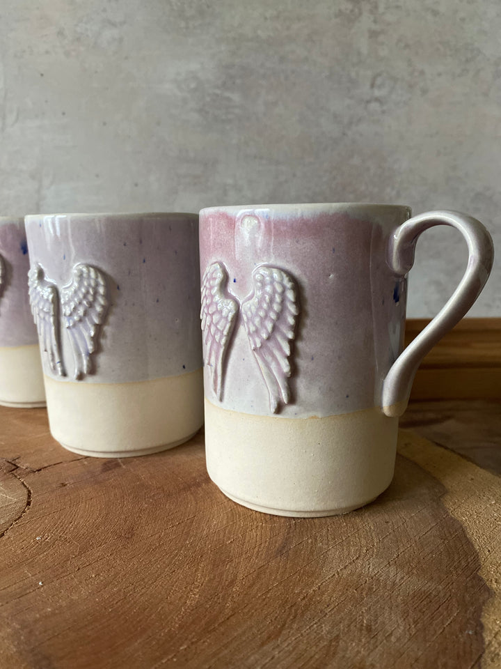 Decorative ceramic item with angel wing design on a wooden surface