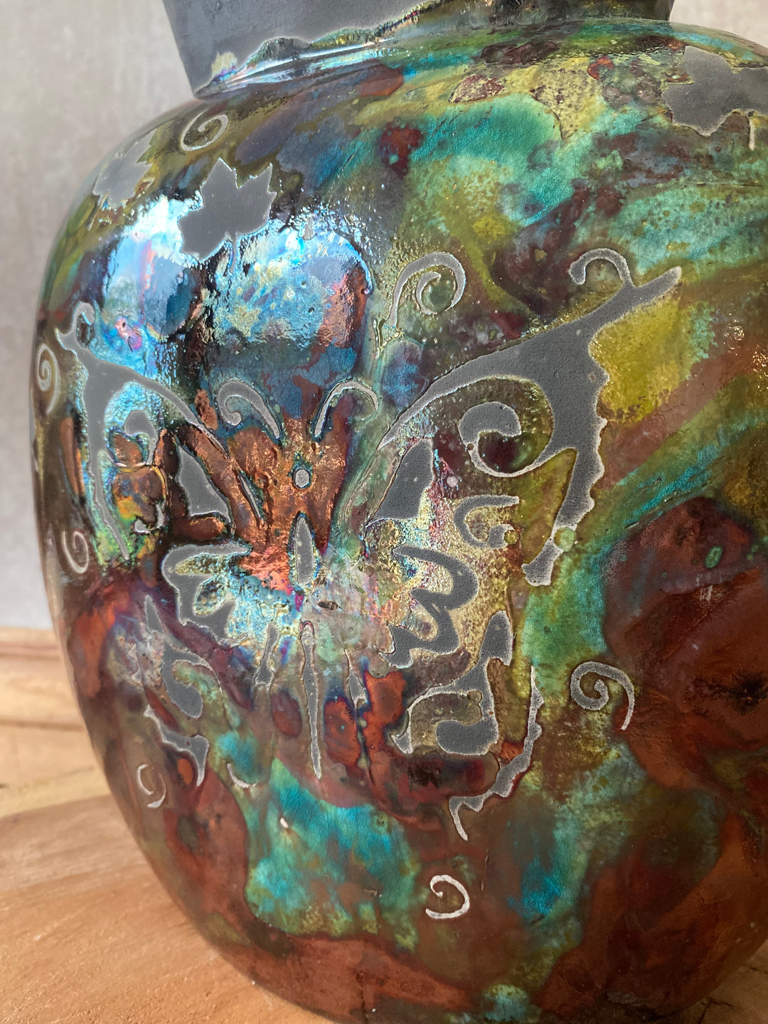Decorative ceramic bowl with metallic sheen and engraved design on a wooden surface