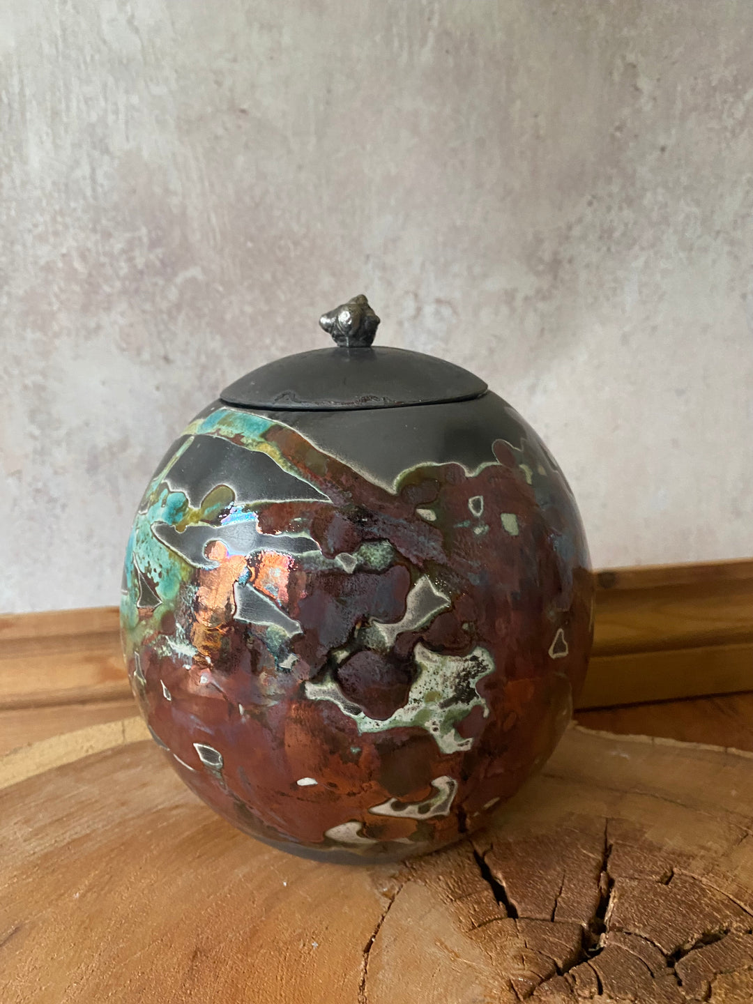 Decorative metal ball with a textured surface on a wooden and stone background