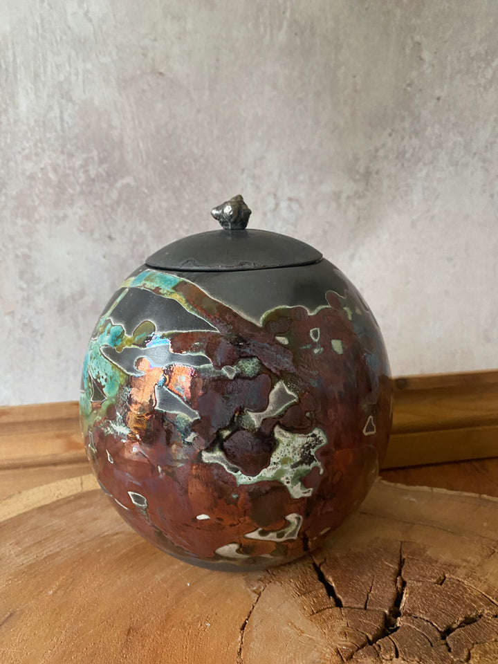 Decorative metal ball with a textured surface on a wooden and stone background
