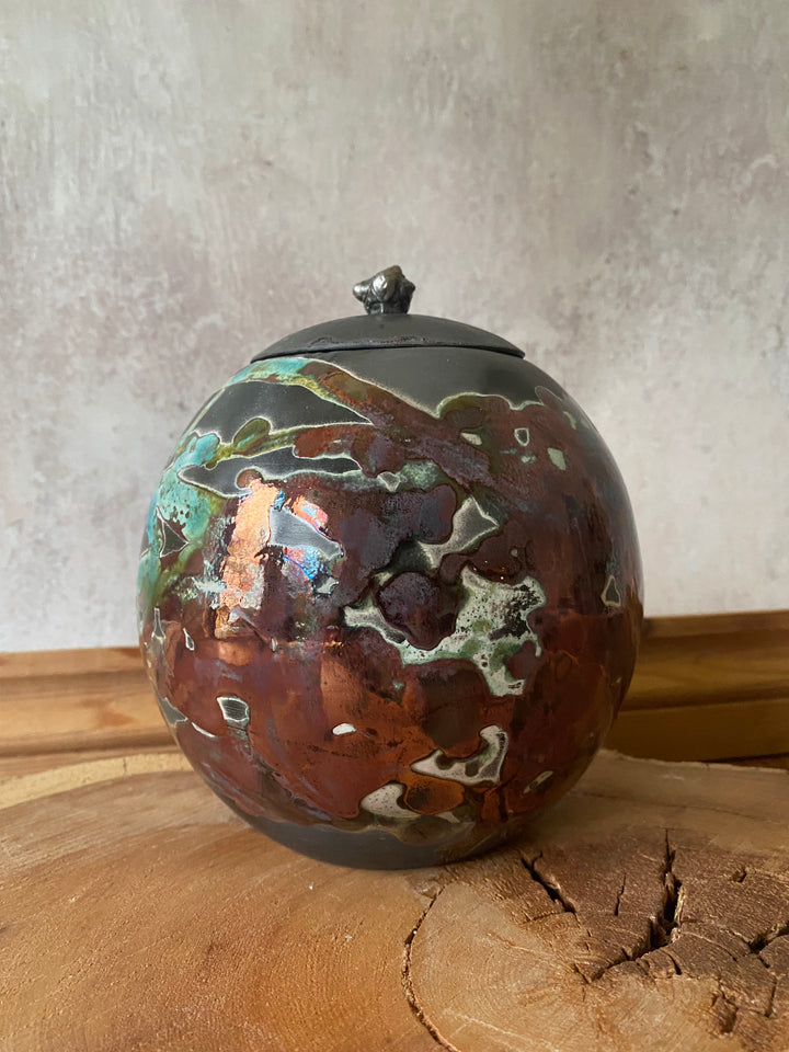 Decorative ceramic ball with metallic glaze on a wooden surface