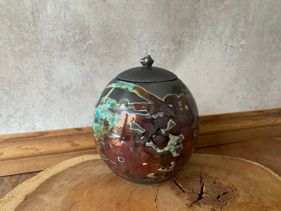 Decorative ceramic urn with a textured surface on a wooden surface.