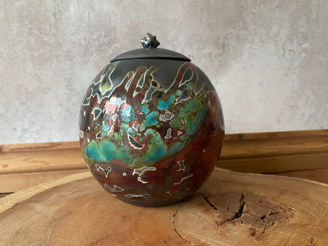 Ceramic urn with decorative glaze on a wooden surface