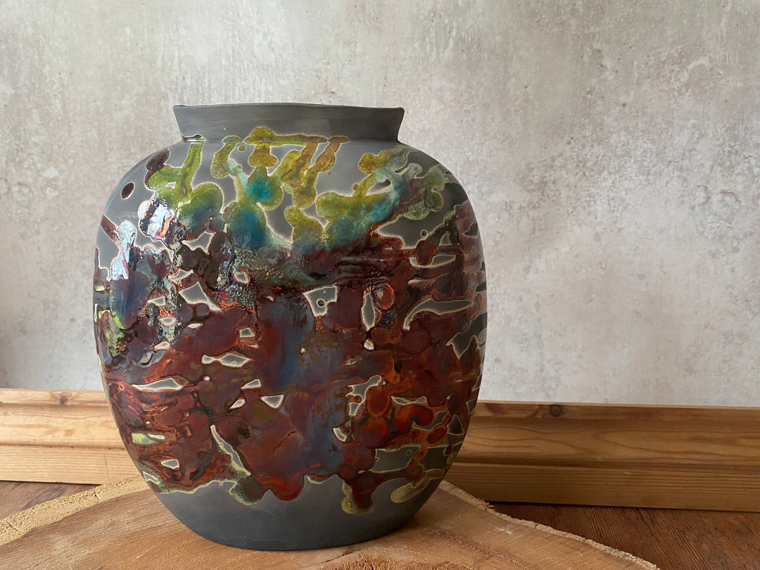 Decorative ceramic vase with multicolored glaze on a wooden surface.