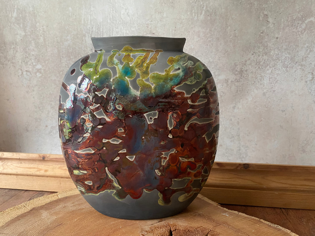 Decorative ceramic vase with multicolored glaze on a wooden surface.