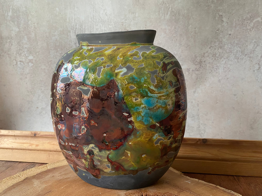 Decorative ceramic vase with multicolored glaze on a wooden surface.