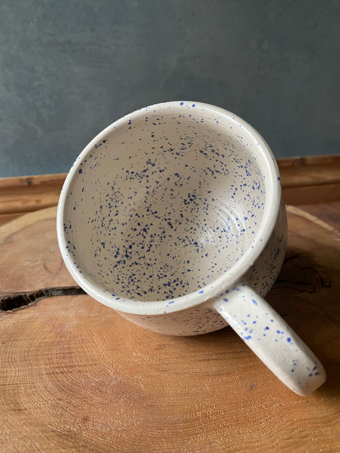 Speckled ceramic mug on a wooden surface with a grey background